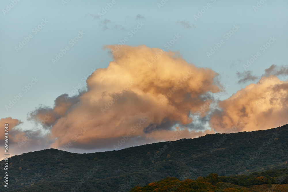 Orange sunset clouds over dark mountains and forest. Sunset background for site.