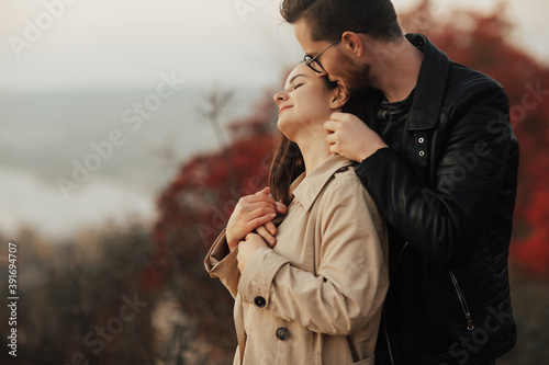 Close-up of beautiful passionate couple is hugging in the autumn park. Man gently touching the neck of his girl.