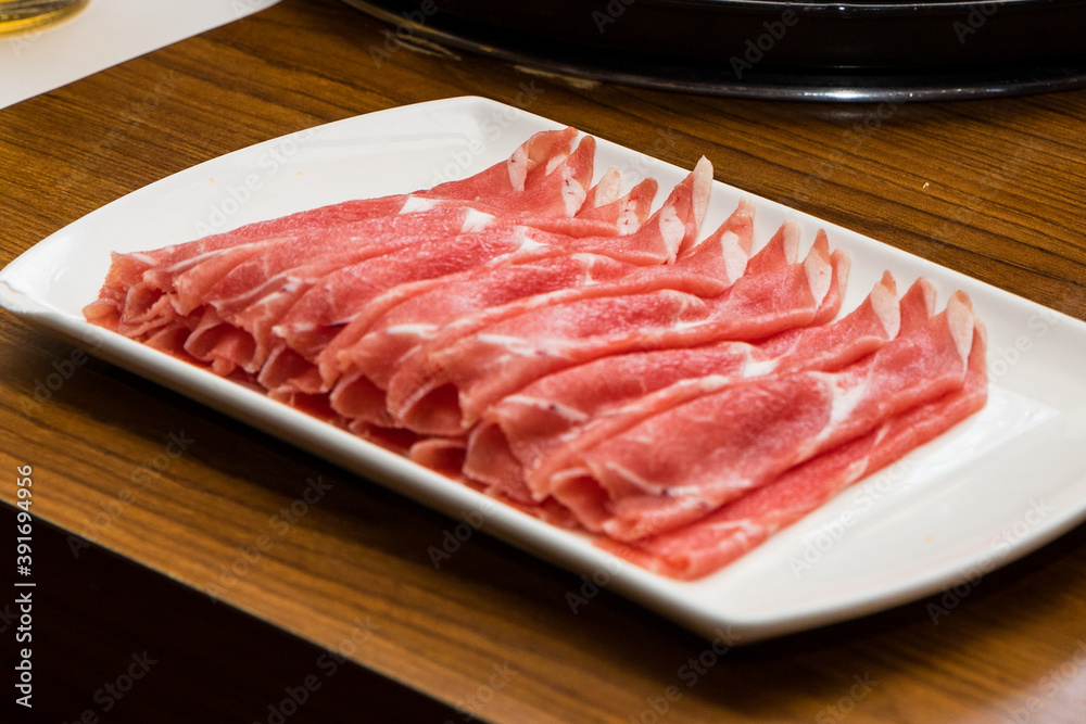 Thin sliced raw beef meat in a white plate for Shabu-shabu Hot Pot cuisine Thin sliced raw beef meat in a white plate for Shabu-shabu Hot Pot cuisine