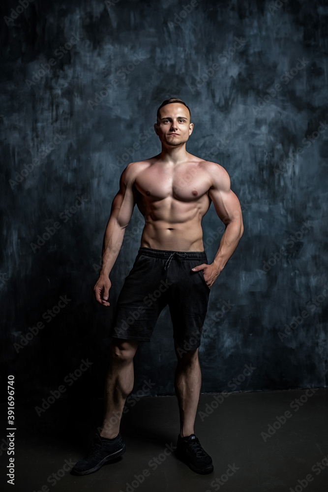 Handsome athletic man posing on black background.