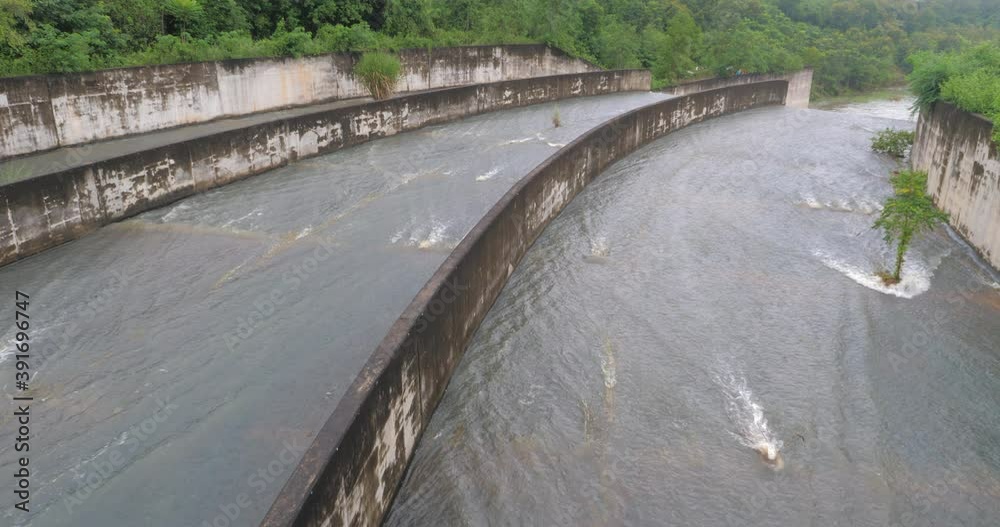 Plenty of water falling from the concrete reservoir dam spillway, overflow floodway in the rural