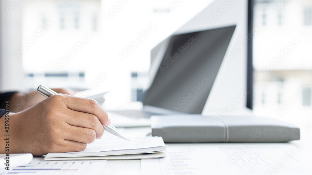 Young Asian woman analyzing financial work graph data in office.