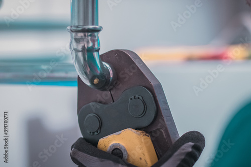 Plumber using pipe fastener or battery press tool to crimp heating or warm water pipes together. House renovation.