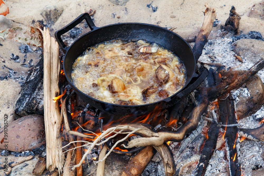 Pieces of lamb with onion are fried in boiling oil on the fire. As a stage in the preparation of traditional pilaf. Pieces of lamb with onion are fried in boiling oil on the fire. As a stage in the preparation of traditional pilaf.