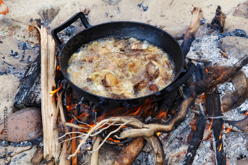 Pieces of lamb with onion are fried in boiling oil on the fire. As a stage in the preparation of traditional pilaf.