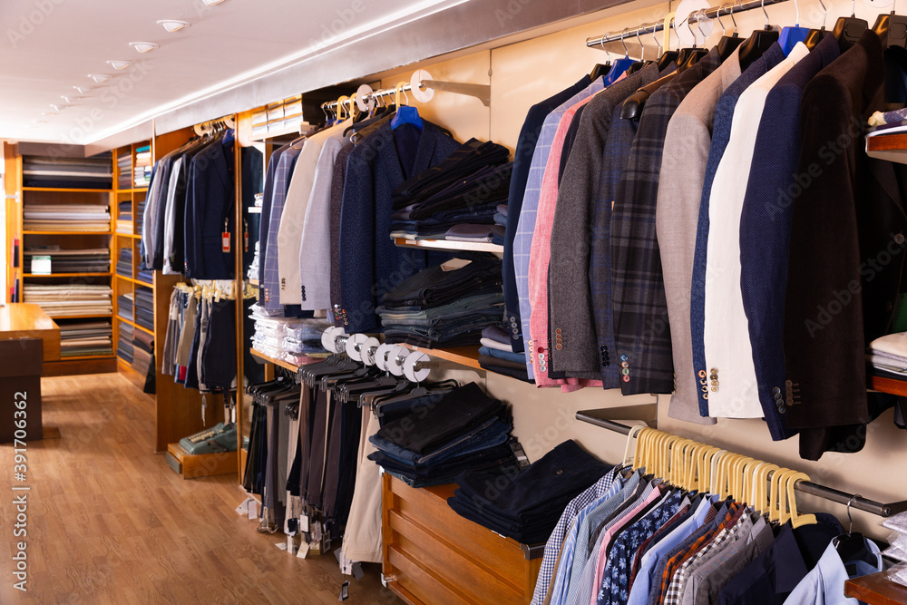 Interior of modern men clothing store with variety of suit coats, dress pants, shirts on display