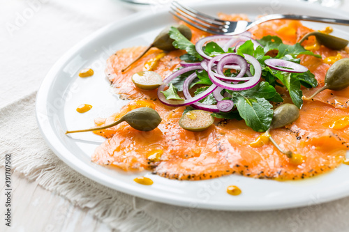 Salmon carpaccio and arugula salad with onions and capers