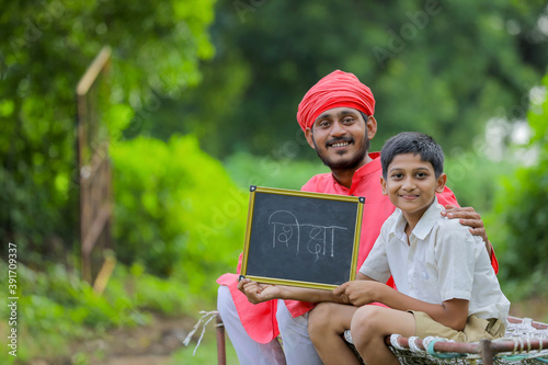 farmer with his child showing shiksha word writing in marathi language on chalkboard photo