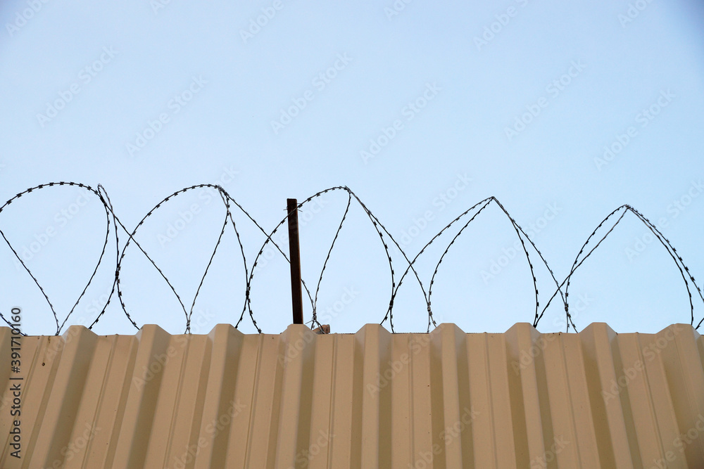 fence with barbed wire in jail against blue sky fence with barbed wire in jail against blue sky