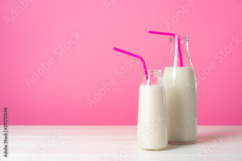 Fotografie Two glass bottles of milk or milkshake against pink background