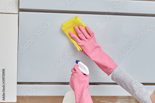 Women's hands in pink rubber gloves doing cleaning in the kitchen. Modern bright kitchen. Performing a home routine. Cleanliness in the house.