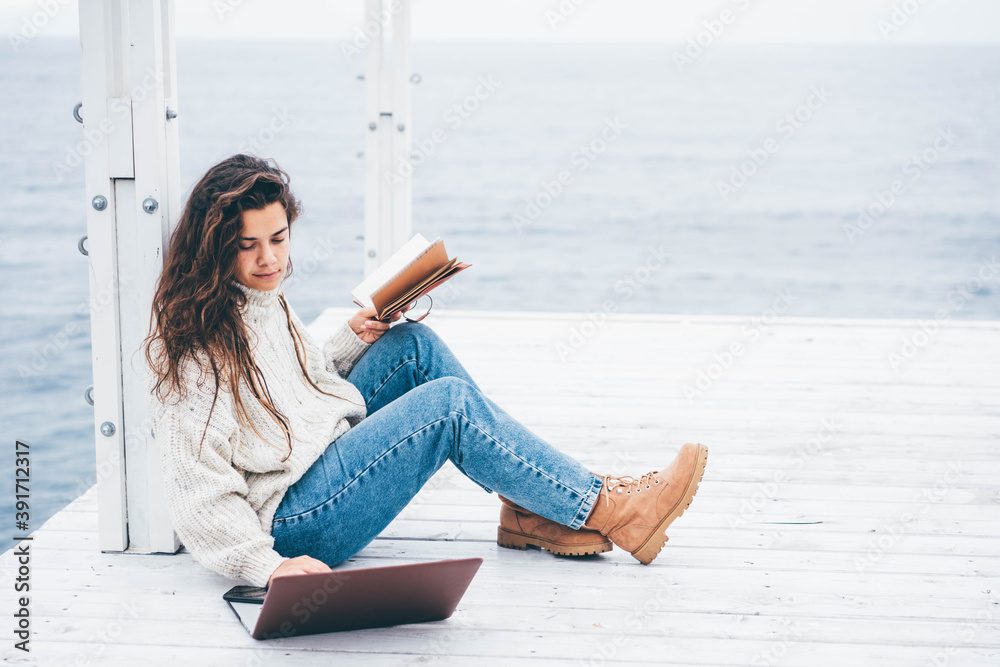 Young woman using laptop computer on winter sea. Freelance work concept