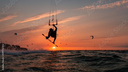 Fototapeta Naklejka Na Ścianę i Meble -  Silhouette of kitesurfer jumping with grab in the orange sunset at the baltic sea