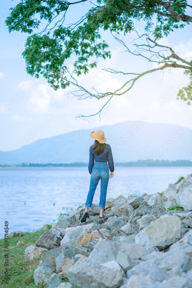Obraz premium portrait woman stand on the rock in sea landscape with mountain relax and calm in sunny day concept vacation, relaxing, positive thinking