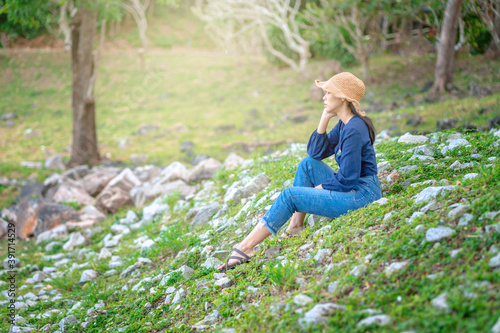 portrait young woman sitting on a green grass and rock in summer. sunny day .beautiful woman vacation calm organic positive thinking mood romantic woman in hat