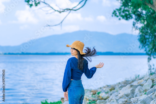 portrait woman blow her hair in sea landscape with mountain  relax and calm in sunny day concept vacation, relaxing, positive thinking, have fun, asian woman, shooting pose