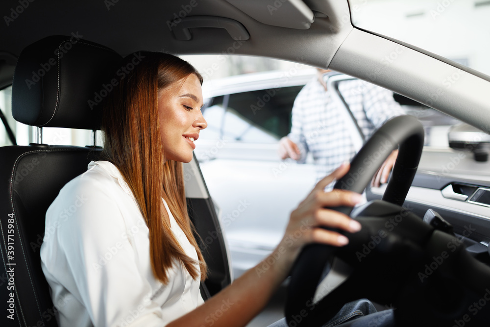 Young attractive woman looking for a new car in a showroom Young attractive woman looking for a new car in a showroom