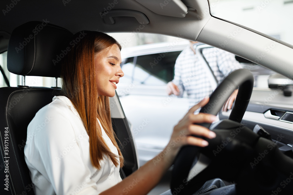 Young attractive woman looking for a new car in a showroom