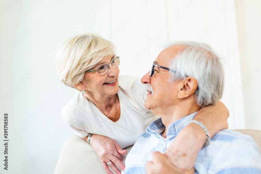 Portrait of happy senior couple embracing each other in living room at home. Elderly couple lookin each other with love and smilling Portrait of happy senior couple embracing each other in living room at home. Elderly couple lookin each other with love and smilling