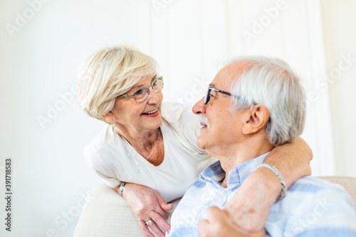 Portrait of happy senior couple embracing each other in living room at home. Elderly couple lookin each other with love and smilling
