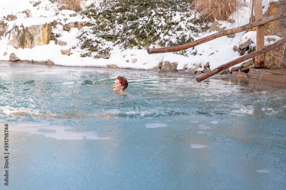 bathing young woman in a frozen lake after sauna