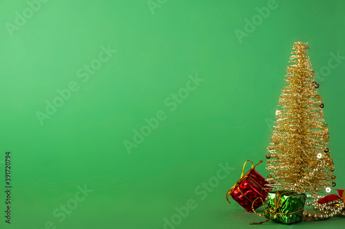 Decorative Christmas tree with gifts on green background. Space for text photo