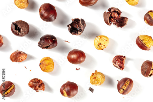 Roasted chestnuts in various stages of peeling, shot from the top on a white background, a flat lay photo