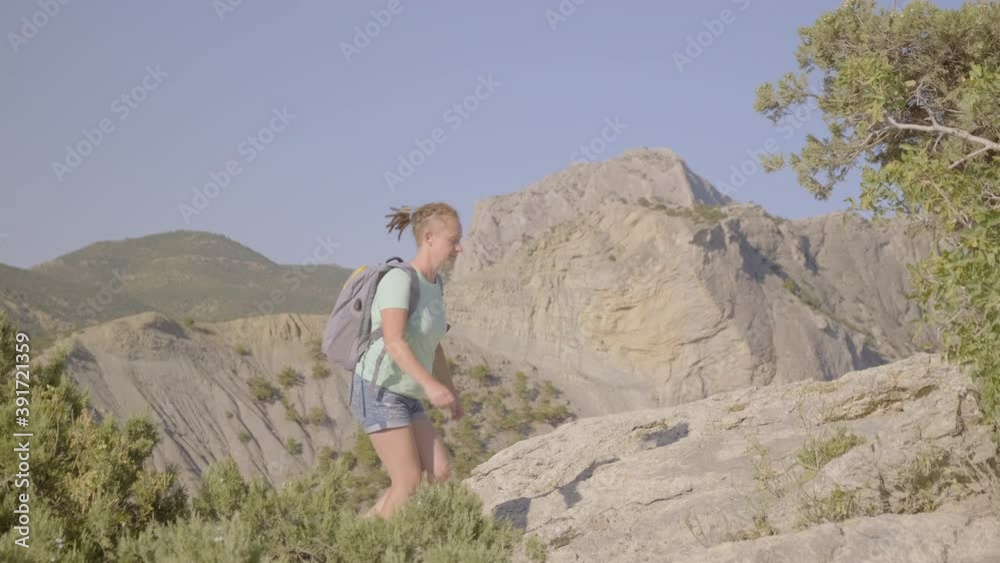 Woman traveler with backpack climbs mountain against blue sky. Woman traveler with backpack climbs mountain against blue sky.