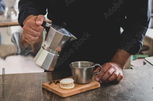 Male Barista preparing fresh espresso in coffee maker for customer in a fancy coffee shop. Cafe owner serving a client at the coffee shop