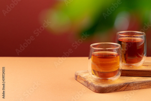 Two glass cups of black tea on beige table