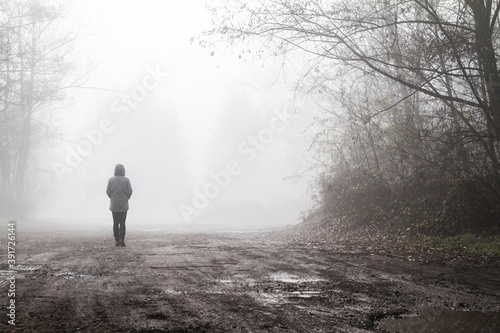 Woman walking in a foggy weather. Mysterious autumn landscape. © Longfin Media