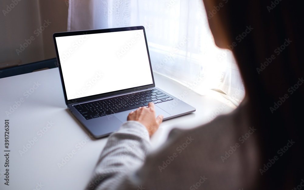 Mockup image of a businesswoman using and touching on laptop touchpad with blank white desktop screen on the table