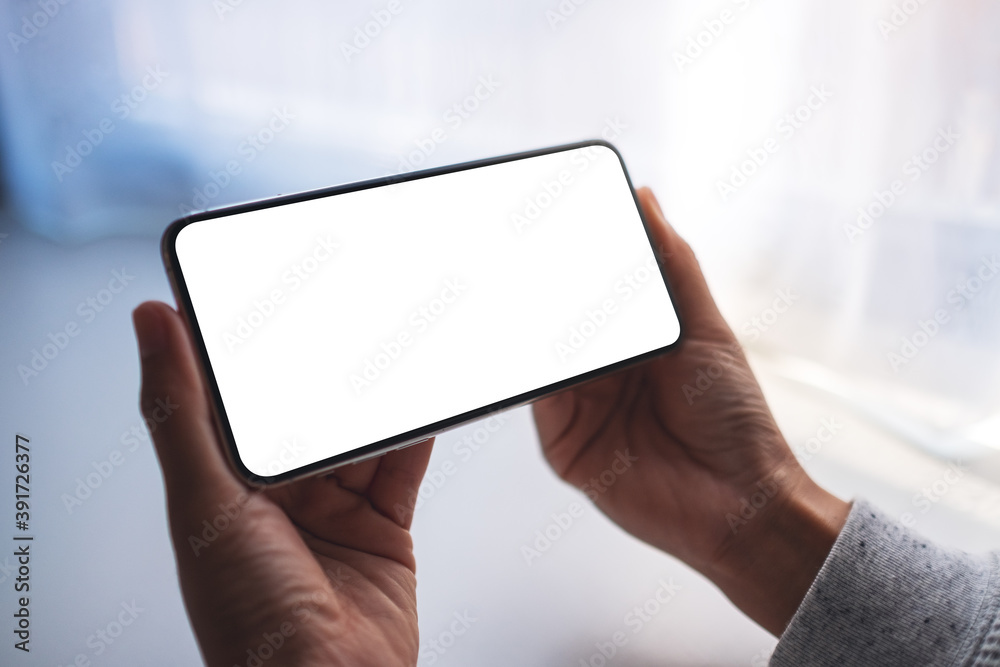 Mockup image of a woman holding mobile phone with blank white desktop screen Mockup image of a woman holding mobile phone with blank white desktop screen