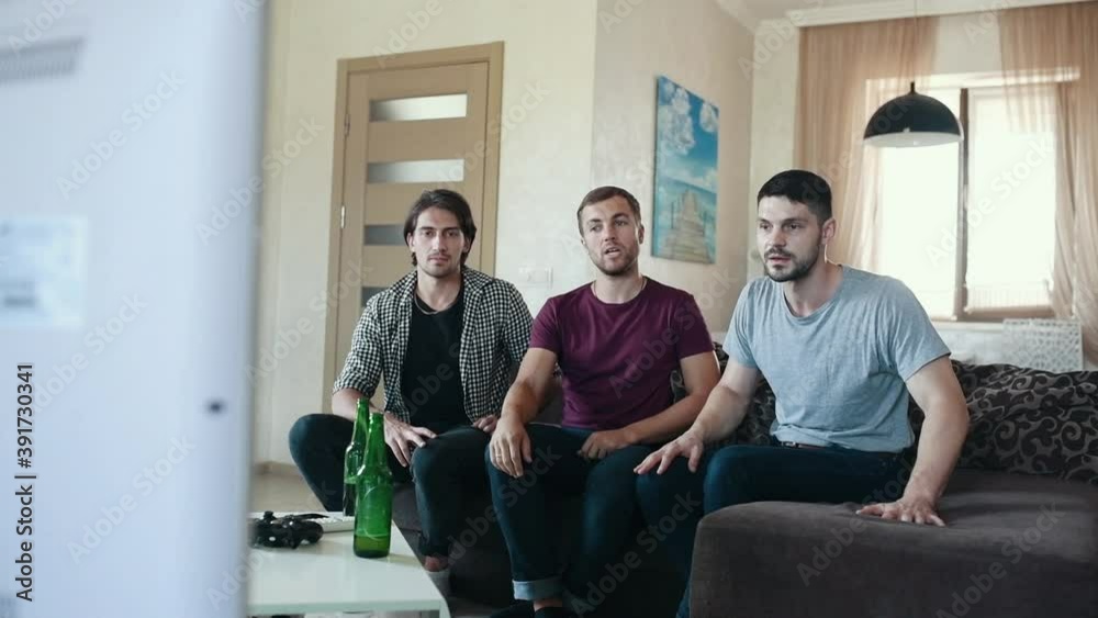 Three people watching soccer indoors by TV. Angry friend screaming about loss. Three people watching soccer indoors by TV. Angry friend screaming about loss.