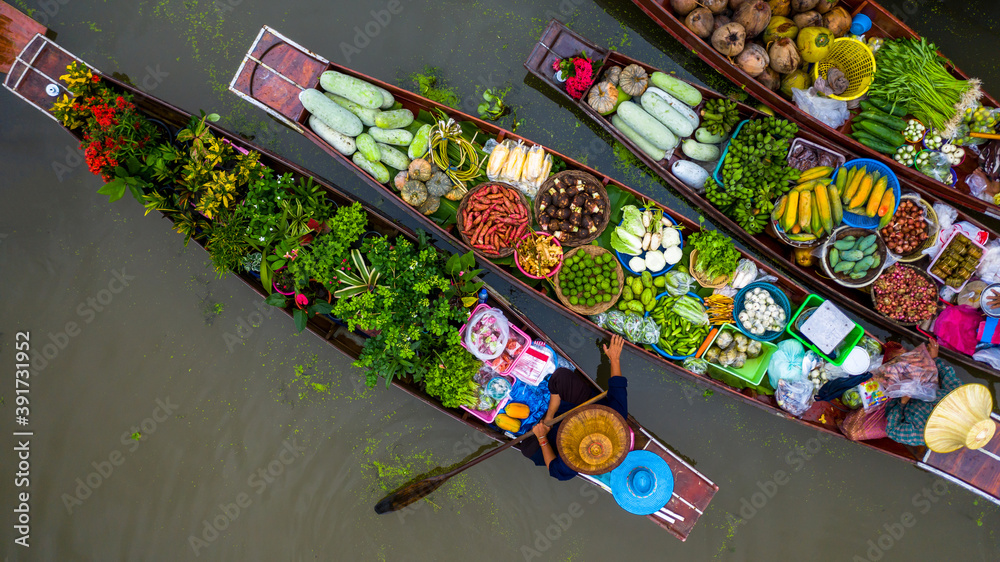 Fototapeta premium Aerial view famous floating market in Thailand, Damnoen Saduak floating market, Farmer go to sell organic products, fruits, vegetables and Thai cuisine, Tourists visiting by boat, Ratchaburi, Thailand
