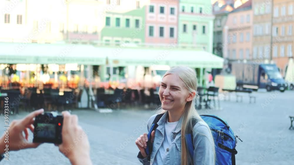 Medium shot of man making photos of female tourist on the view of city market square. Blonde woman making faces and smiling. Medium shot of man making photos of female tourist on the view of city market square. Blonde woman making faces and smiling.