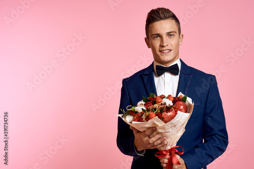 Handsome man in a classic suit with a bouquet of flowers on a pink background holidays bow tie model