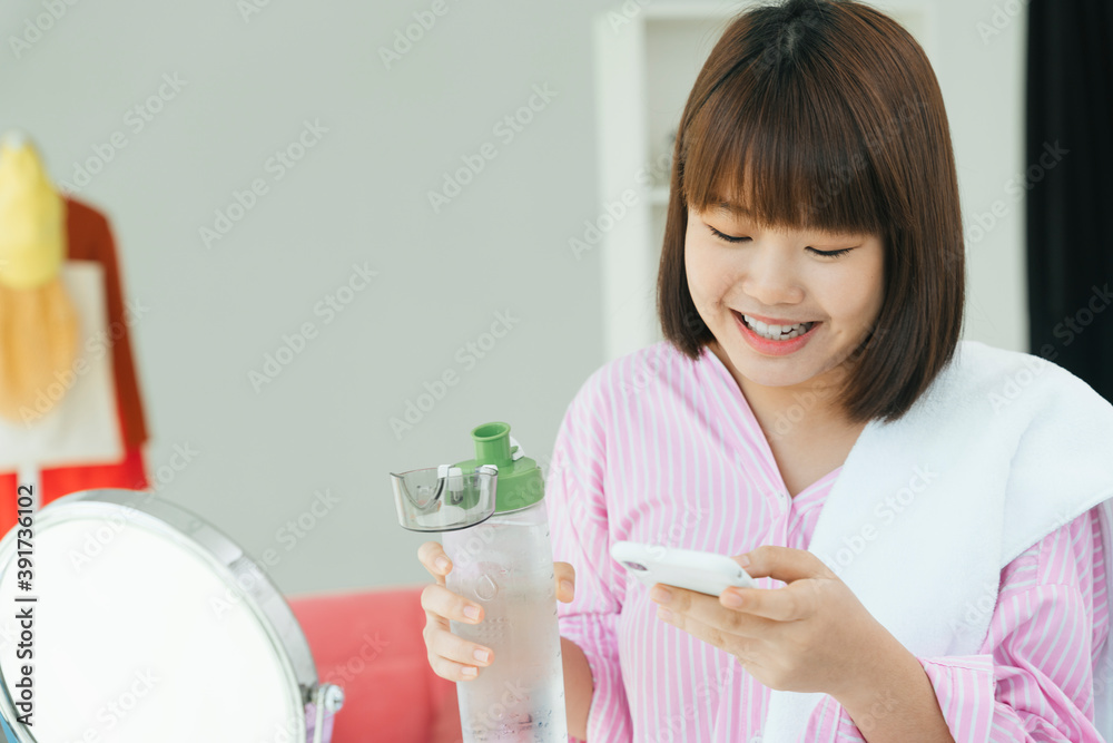 Young asian thai short hair bob hairstyle drinking water from bottle and using smartphone. Young asian thai short hair bob hairstyle drinking water from bottle and using smartphone.