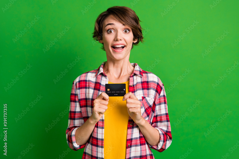 Photo of impressed cute short hairdo girl hold card wear orange cloth isolated over vivid green color background Photo of impressed cute short hairdo girl hold card wear orange cloth isolated over vivid green color background