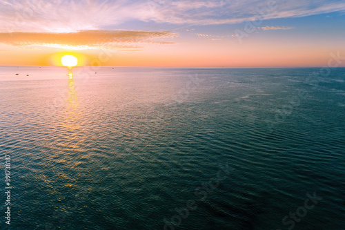 Aerial view of sun setting over calm ocean water