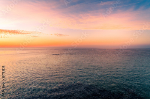 Minimal aerial seascape - sunset over calm water with small lonely boat