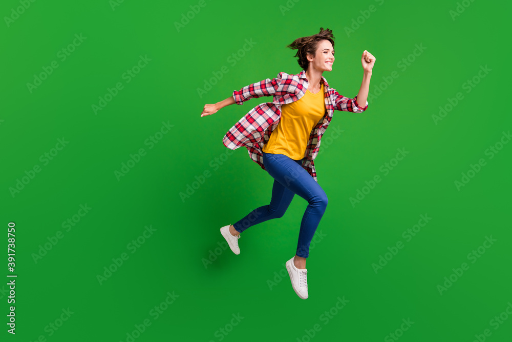 Full size profile photo of cute sweet girl jumping run hands fists wear trousers shirt sneakers isolated on green color background
