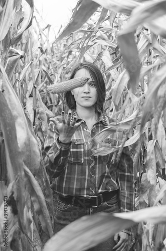 Black and white shot of Young woman farmer with corn harvest. Worker holding autumn corncobs. Farming and gardening