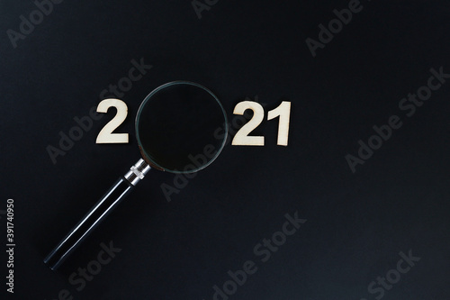 A magnifying glass and block letters in 2021 on black background photo