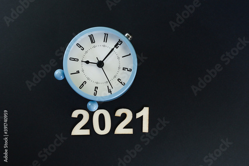 Block letters on the year 2021 with alarm clock on black background 