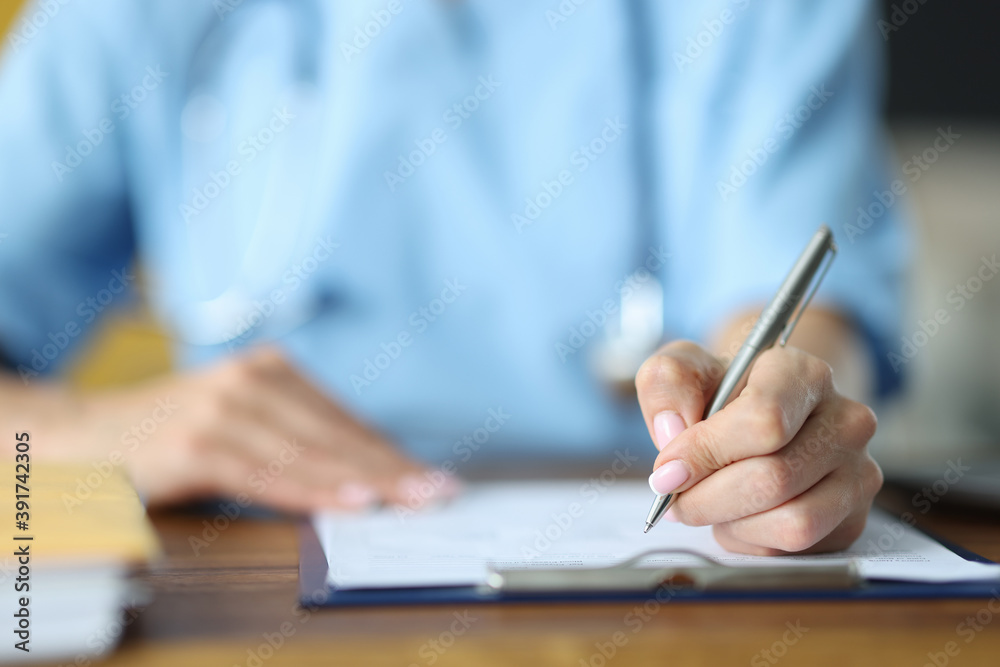 Doctor holding in hand silver pen on documents at table in office close-up. Documentation in medicine concept Doctor holding in hand silver pen on documents at table in office close-up. Documentation in medicine concept