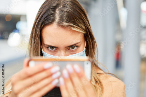 Frau mit Gesichtsmaske macht Selfie bei Covid-19 Pandemie