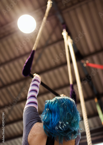 Young woman with blue hair trains on the trapeze