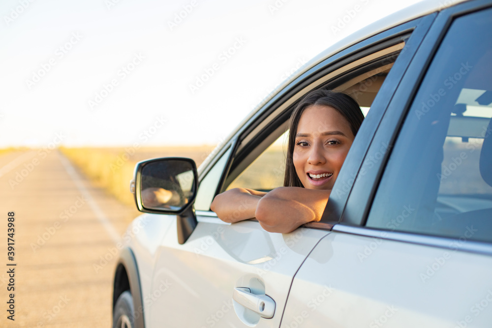 Happy young latin woman enjoying freedom during car roadtrip.