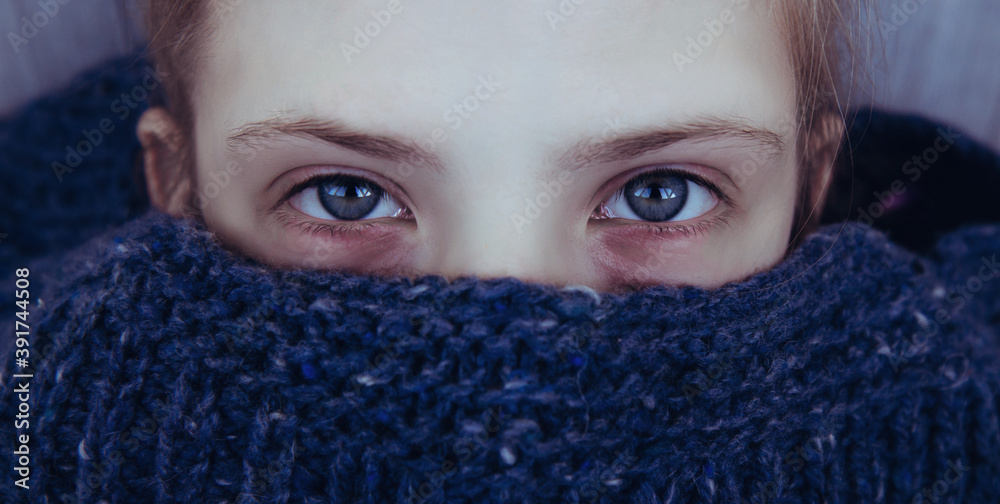 Beautiful girl with tired eyes and bruises under the eyes wrapped herself in a warm blue knitted sweater Beautiful girl with tired eyes and bruises under the eyes wrapped herself in a warm blue knitted sweater